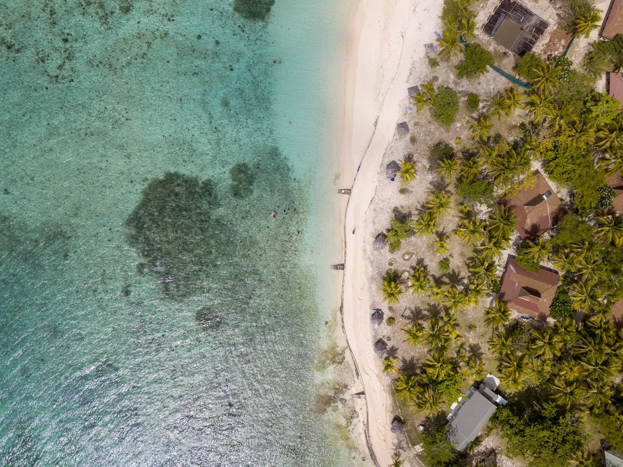 Stunning aerial shot of a pristine beach with turquoise water and lush greenery.