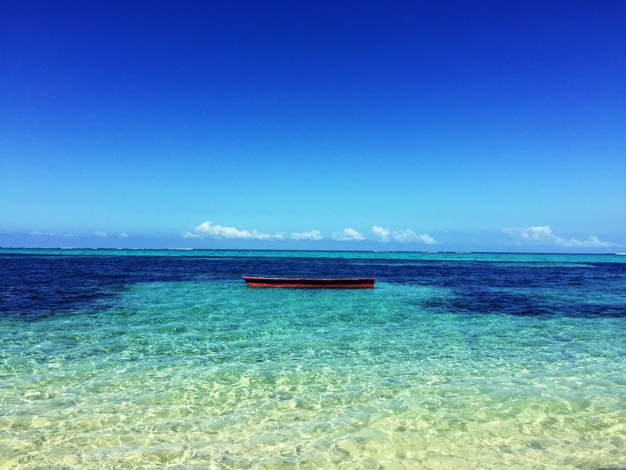 A serene view of a boat floating on clear turquoise waters near Navosa, Fiji.