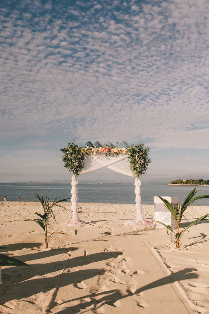 Elegant wedding arch on a sandy beach in Fiji, framed by ocean and sky.