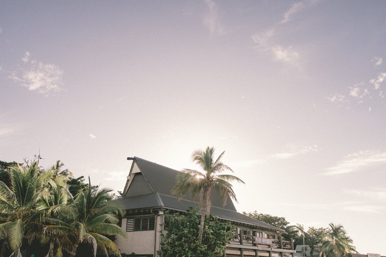 A tropical house surrounded by palm trees in Nadi, Fiji, under a bright summer sky.